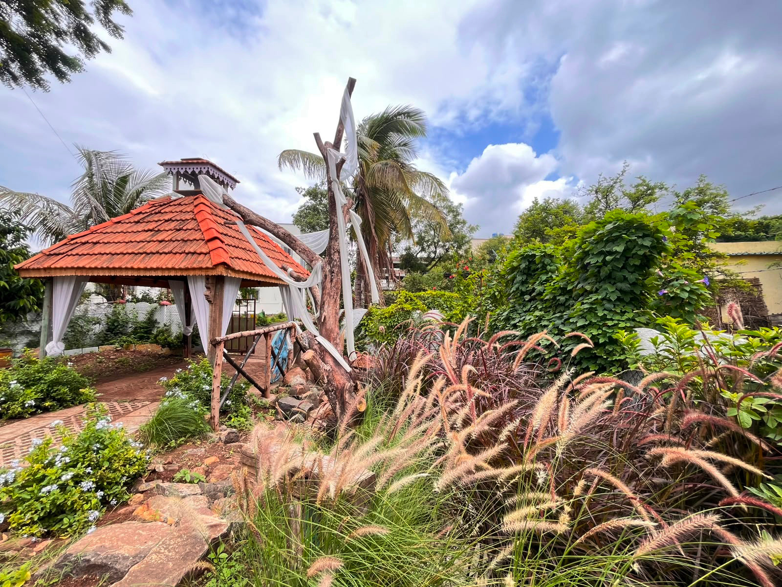 Photo Express outdoor studio garden with a red-tiled pavilion, rustic bridge and ornamental grasses