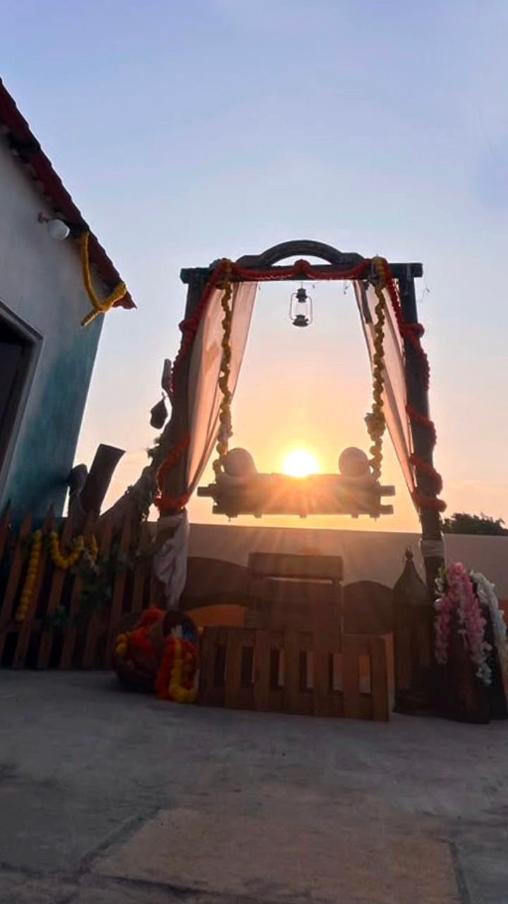 Decorated outdoor studio swing silhouetted against a warm sunset