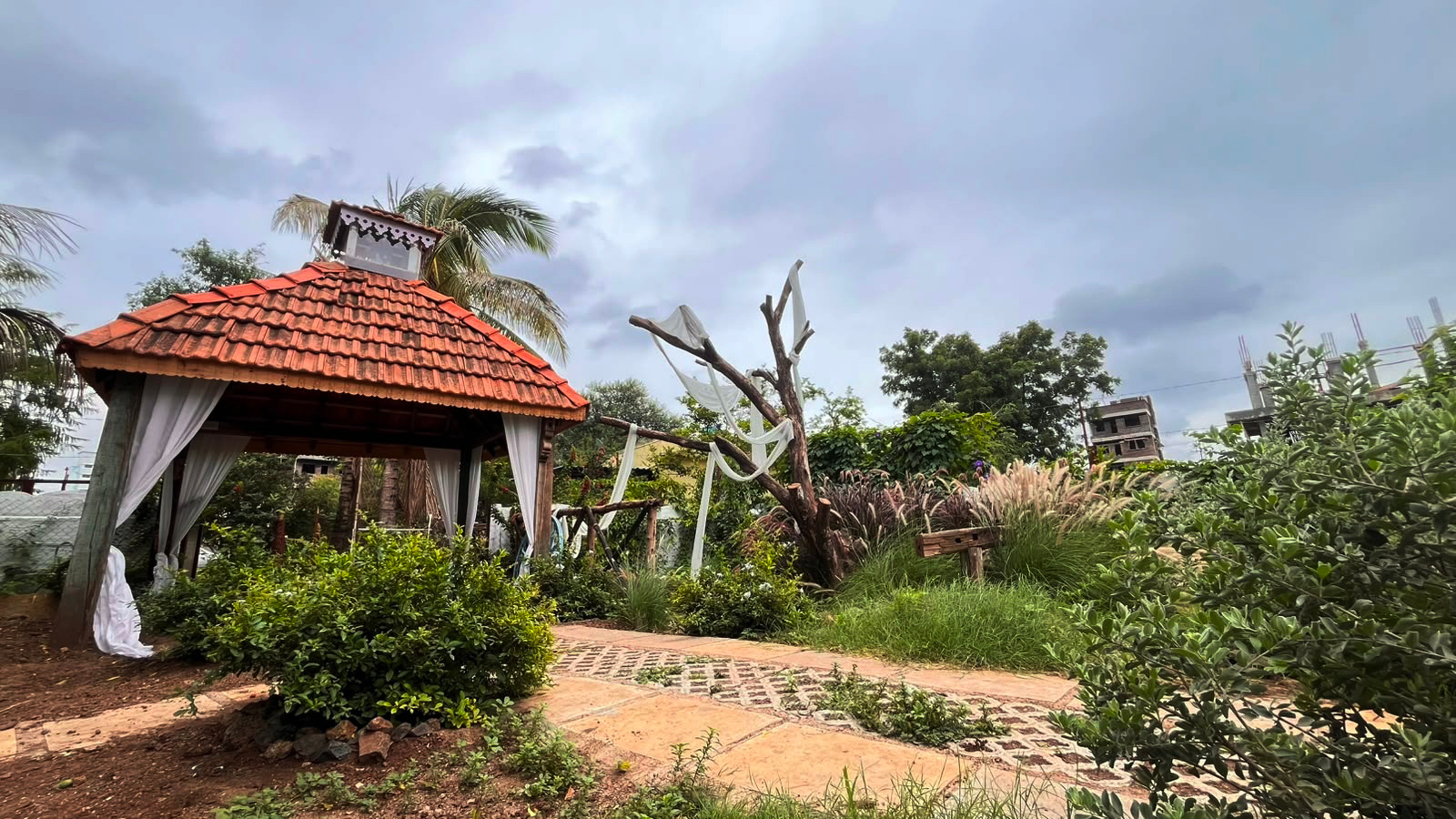 Wide view of the Photo Express portrait garden with a tiled pavilion, paths and layered greenery