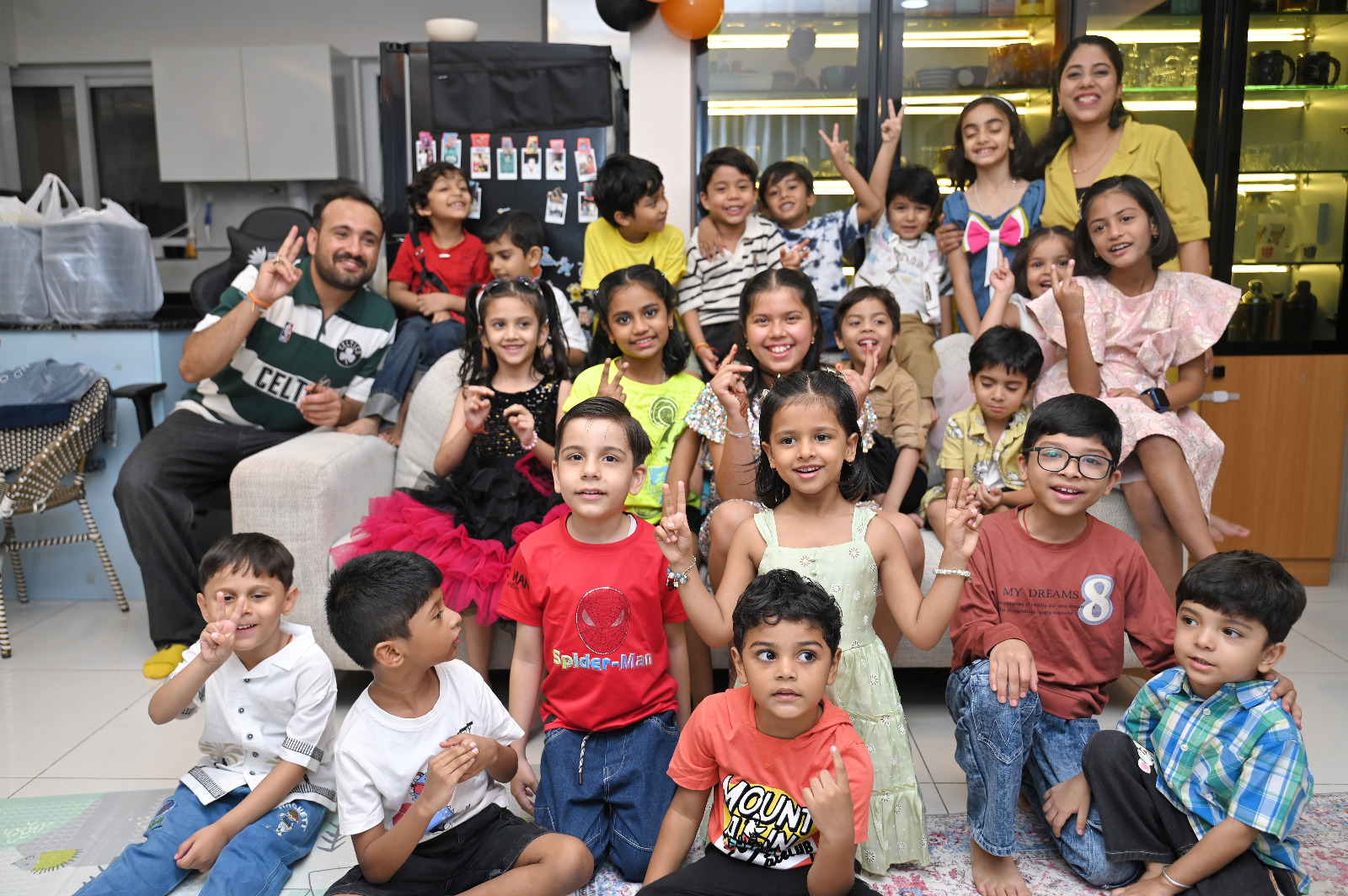 Large group of smiling children and parents gathered together during a fifth birthday party