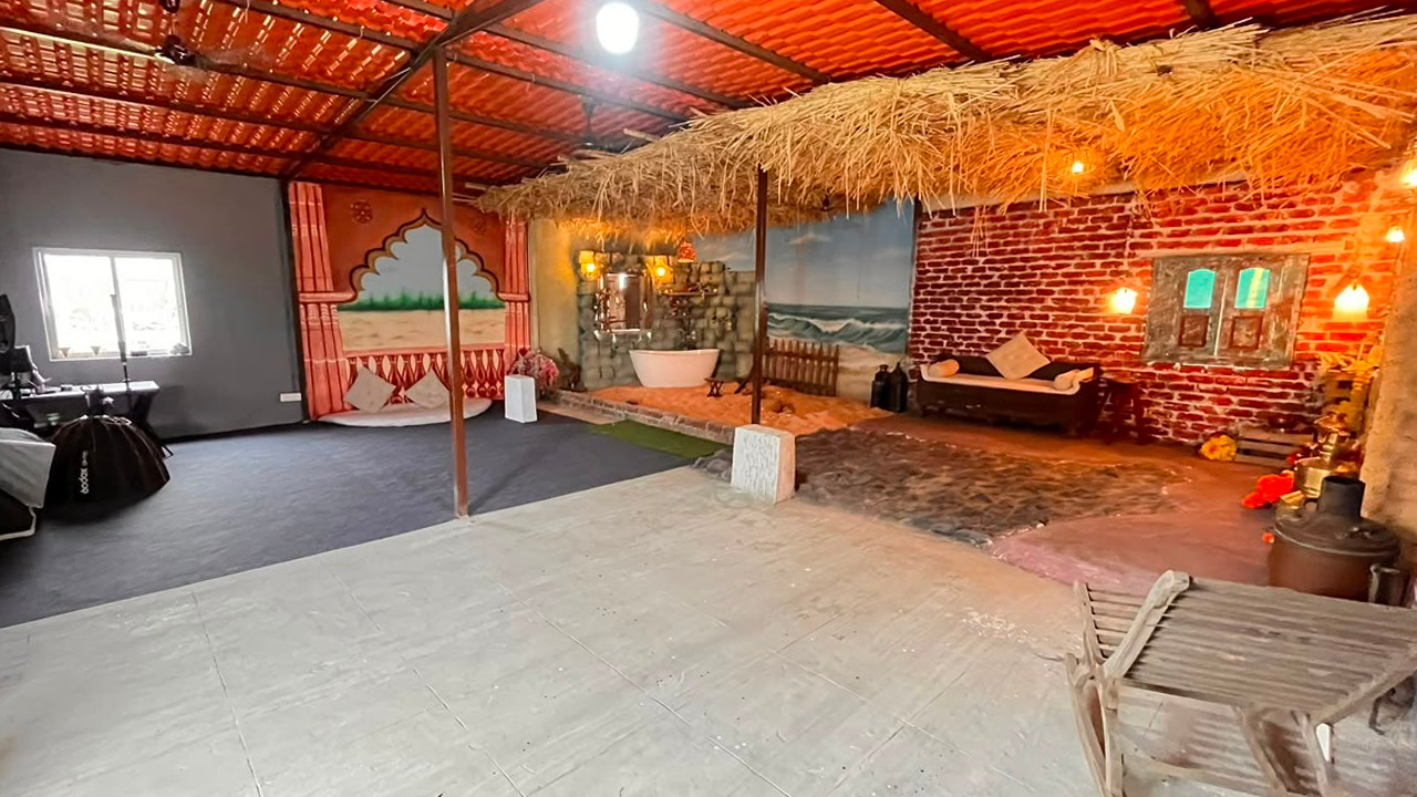 Wide interior view of Photo Express with rustic village, beach and portrait sets under warm lighting